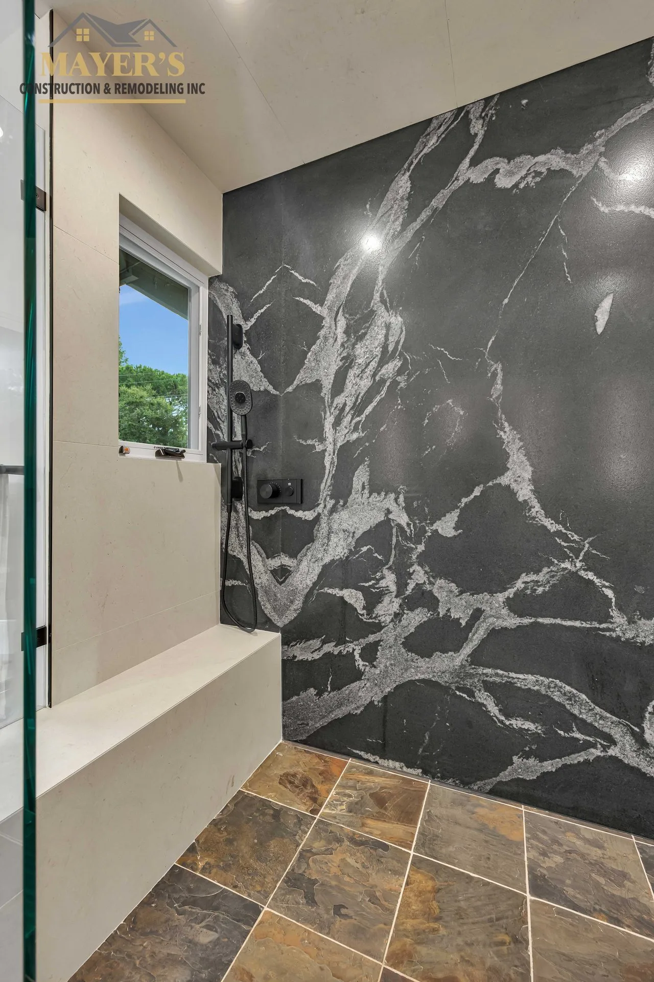 The same walk-in shower shown full height — dark marble slab wall behind glass — Mayer's Construction California portfolio